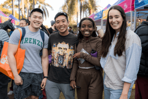 Four students smiling at the camera at a school fair.