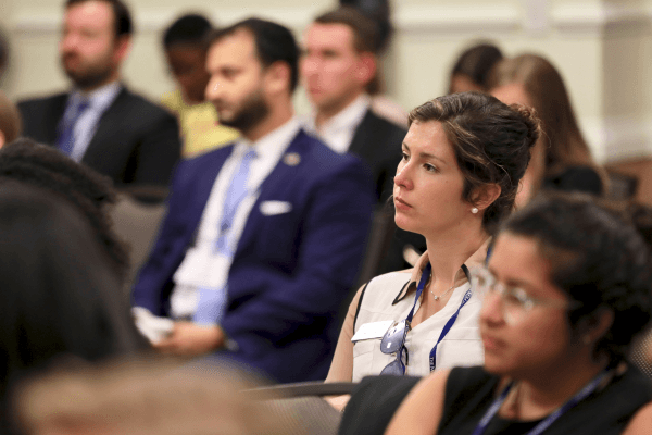 Young professionals seated in an audience watching a presentation.