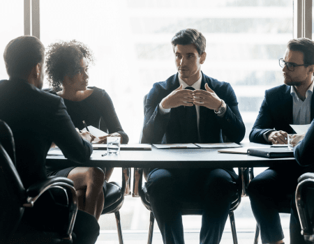 Group of executives talking around a conference table.