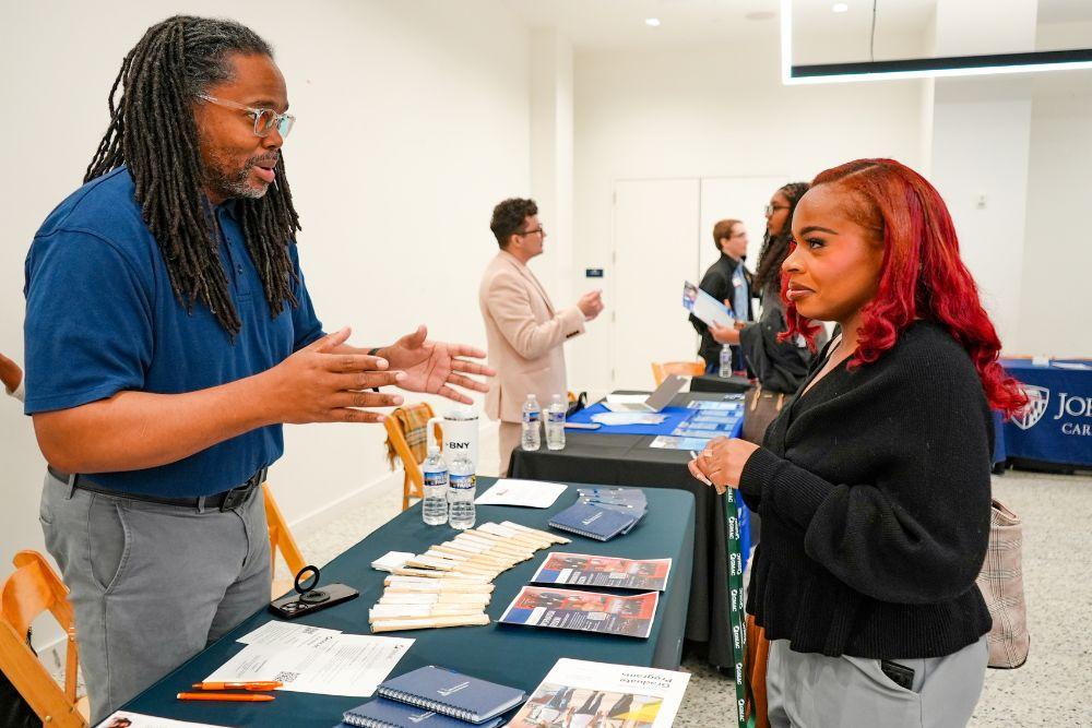 A Howard University admissions representative speaking to a candidate at a networking fair